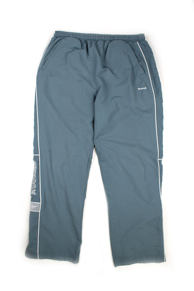 Vintage 00's Reebok blue tracksuit bottoms with white stripes down the side alongside embroidered logo, has a elasticated waist.