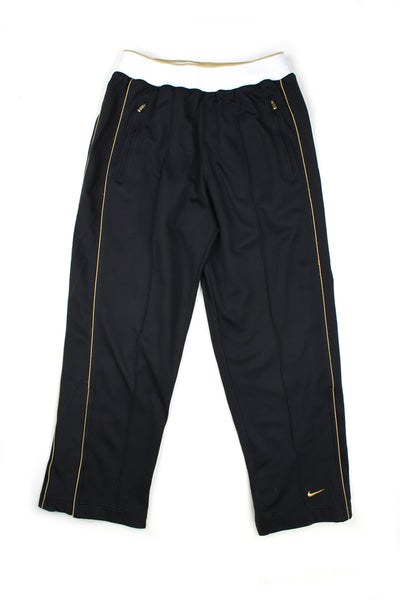 Vintage 00's Nike black pintucked tracksuit bottoms with gold stripes down the side, embroidered swoosh logo, and has a elasticated waist.