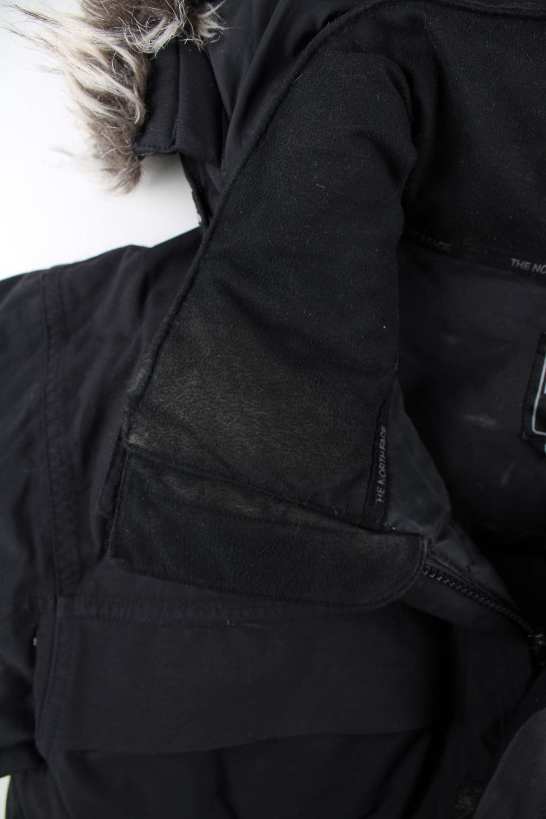 The North Face Parka Coat in a black colourway. Zips up and has multiple pockets, insulated lining, hooded with a detachable faux fur trim, and has the logo embroidered on the front and back.
