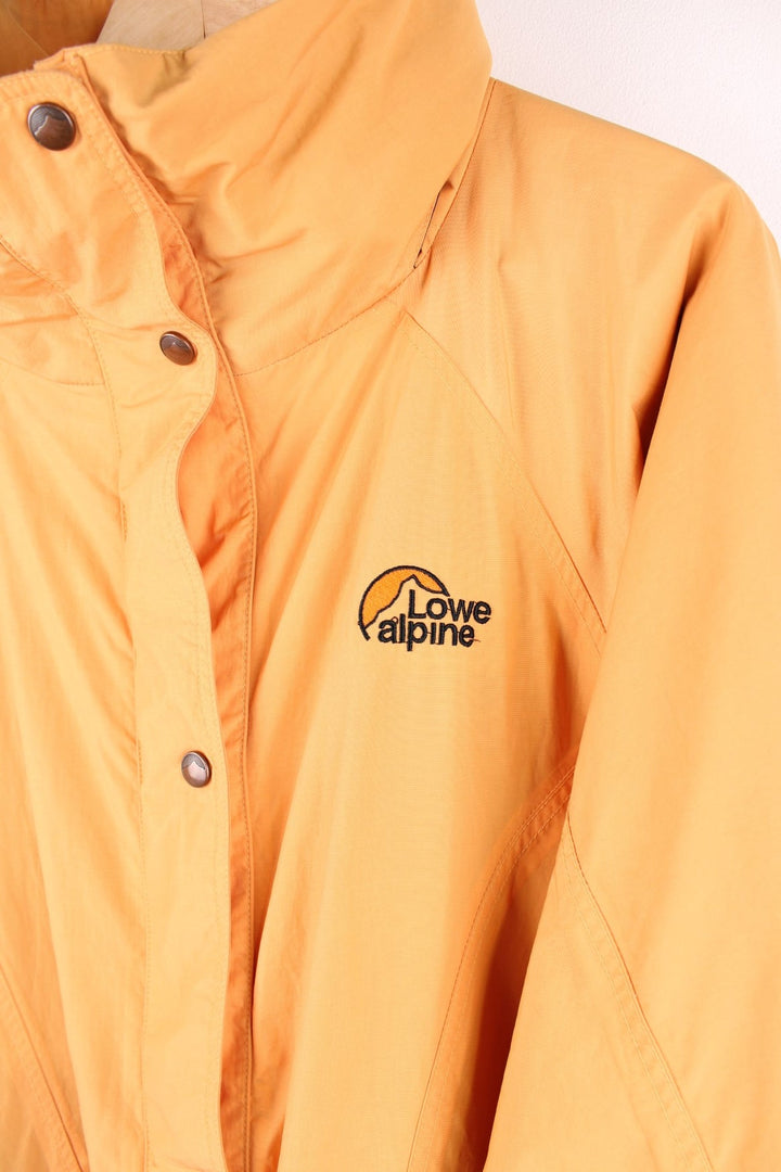Vintage Lowe Alpine waterproof jacket in yellow with zip and snap closure, two front snapped pockets, an inside pocket, and a retractable hood. 