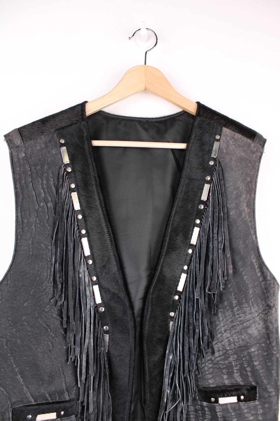 Vintage Leather Gilet in a black colourway with fringing, silver studs/cabochons and an animal hide trim. The gilet has some intentional wear to the leather, as seen in photos.  