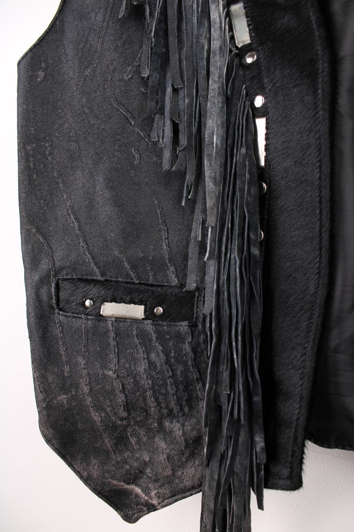Vintage Leather Gilet in a black colourway with fringing, silver studs/cabochons and an animal hide trim. The gilet has some intentional wear to the leather, as seen in photos.  