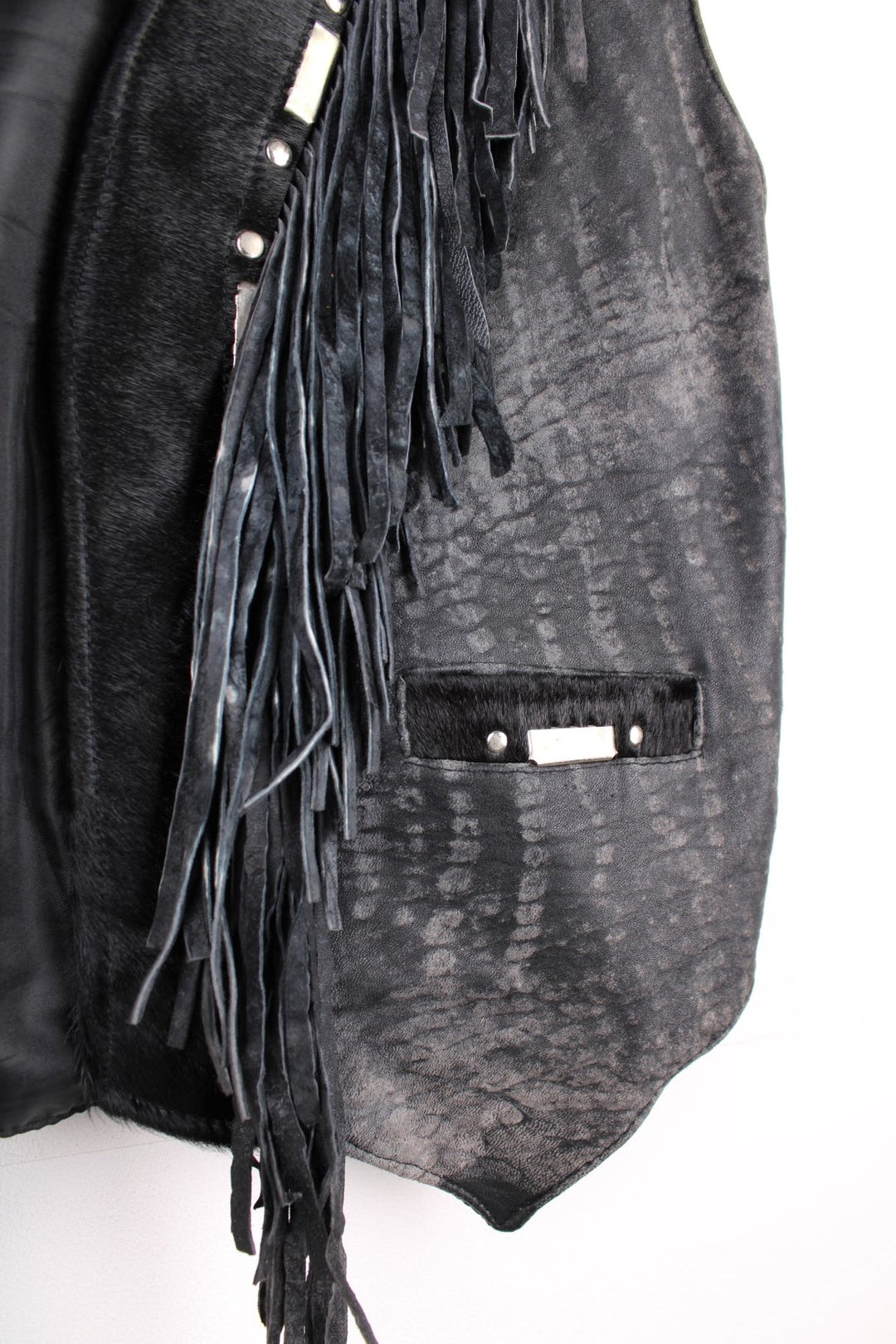 Vintage Leather Gilet in a black colourway with fringing, silver studs/cabochons and an animal hide trim. The gilet has some intentional wear to the leather, as seen in photos.  