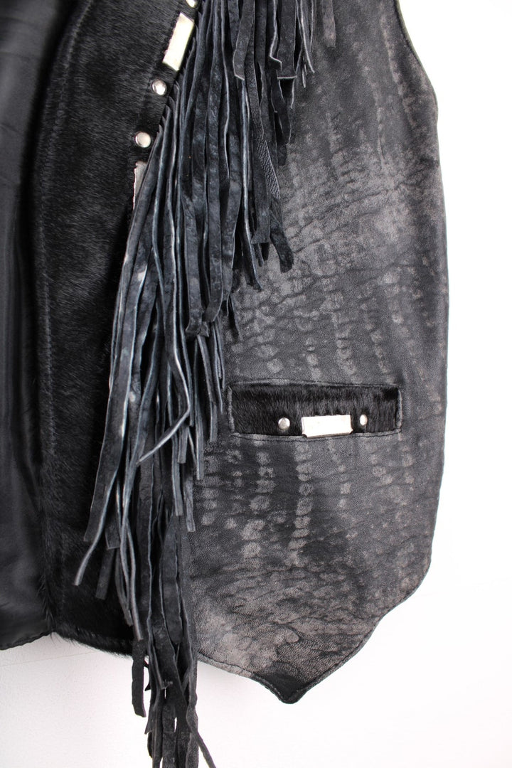 Vintage Leather Gilet in a black colourway with fringing, silver studs/cabochons and an animal hide trim. The gilet has some intentional wear to the leather, as seen in photos.  