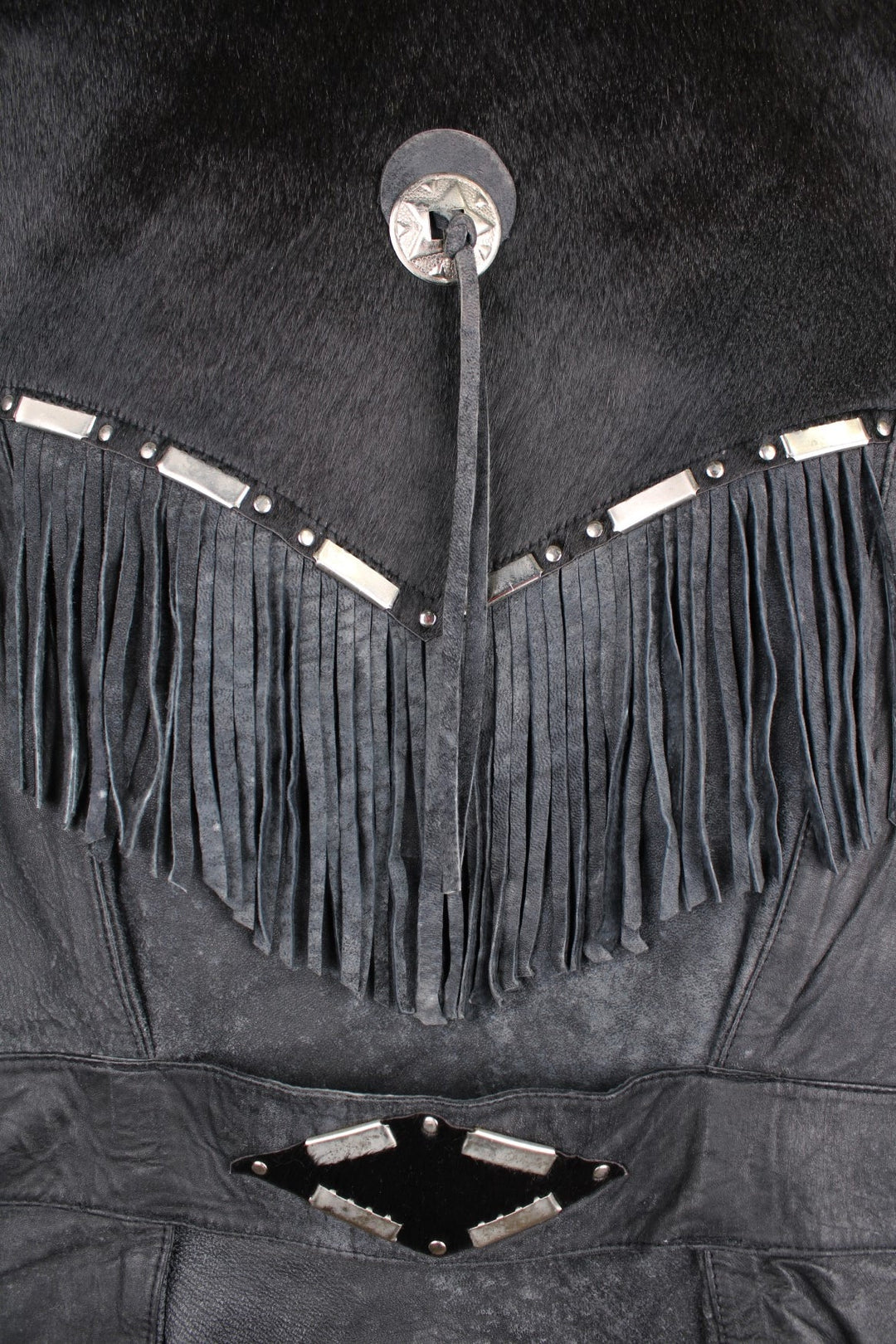 Vintage Leather Gilet in a black colourway with fringing, silver studs/cabochons and an animal hide trim. The gilet has some intentional wear to the leather, as seen in photos.  