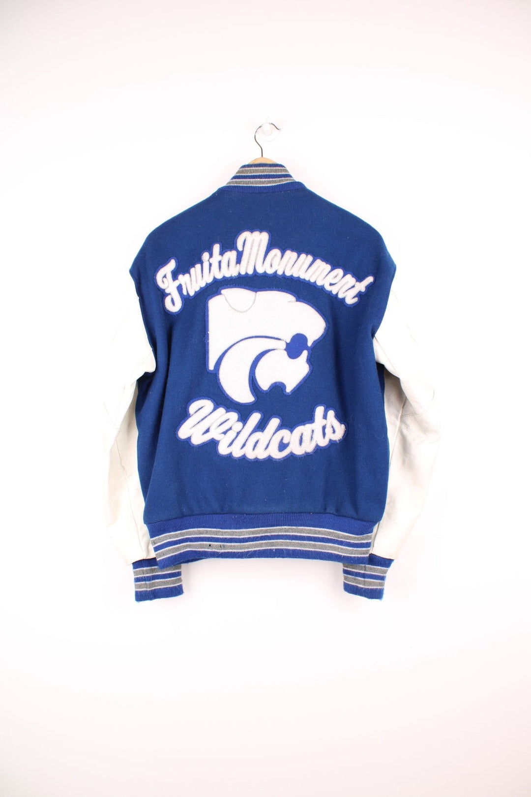 Vintage Delong, Fruita Monument Wildcats varsity jacket in blue with white leather sleeves. Features embroidered letterman patches and large spell out embroidery across the back.  