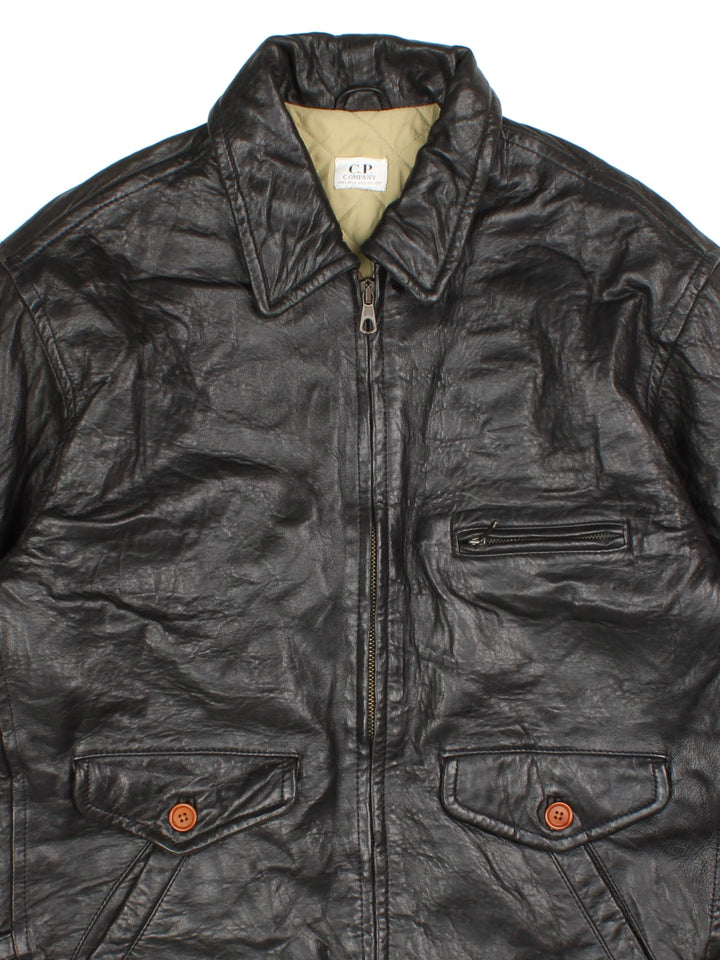 Vintage CP Company Leather Jacket in a black colourway. Zips up and has multiple pockets, insulated with a quilted lining, and has adjustable strap features on the cuffs.