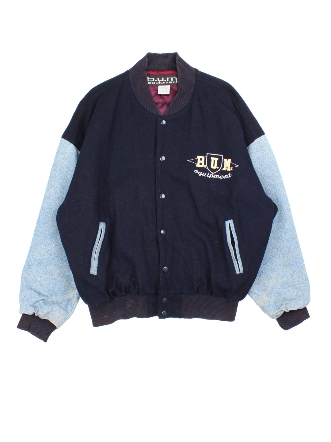 Vintage B.U.M Equipment Varsity Jacket in a blue colourway. Buttons up and has side pockets, denim sleeves, and has the logo embroidered on the front and back.