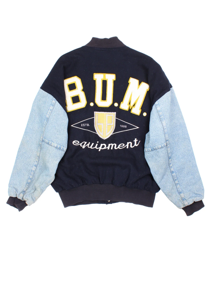 Vintage B.U.M Equipment Varsity Jacket in a blue colourway. Buttons up and has side pockets, denim sleeves, and has the logo embroidered on the front and back.