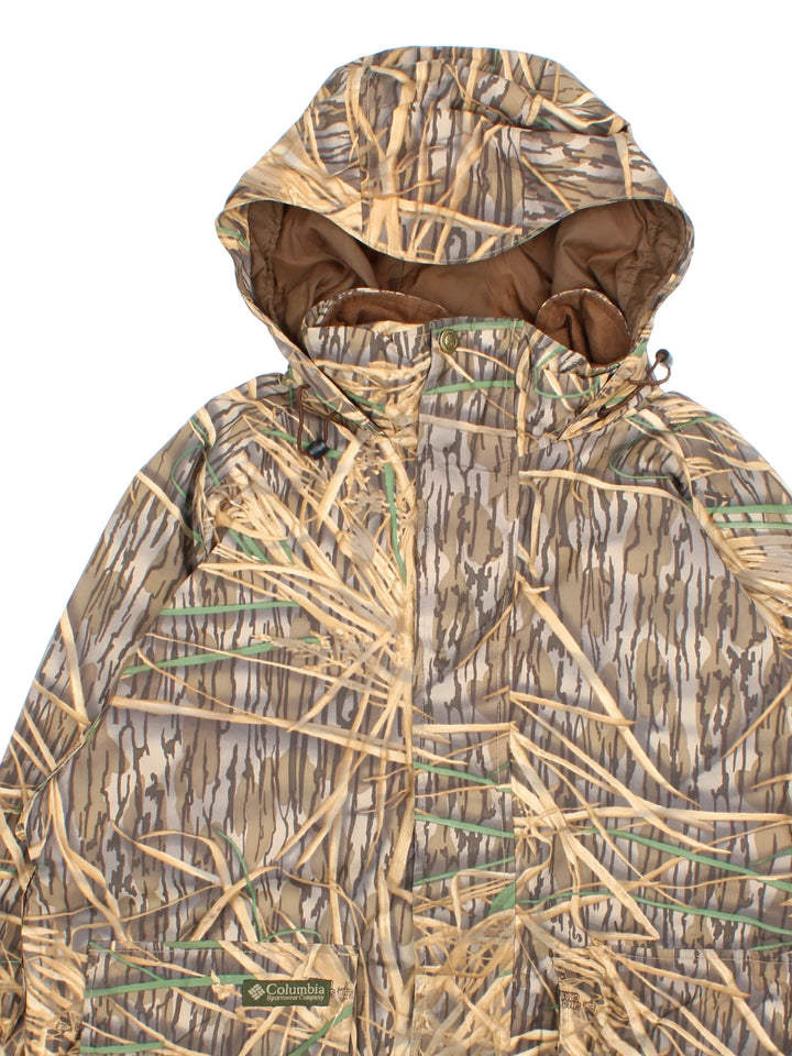 Vintage Columbia Real Tree Camo Jacket in a brown and green colourway. Zips up and has multiple pockets, hooded, and has the logo embroidered on the front.