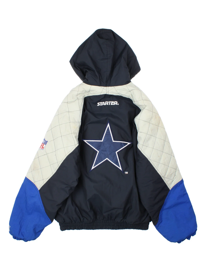 Dallas Cowboys NFL Starter Jacket in a blue and black colourway with grey panelling on the arms. Full zip up with multiple pockets and drawstring hood. Classic logo on the front and sleeves and large star logo on the back.