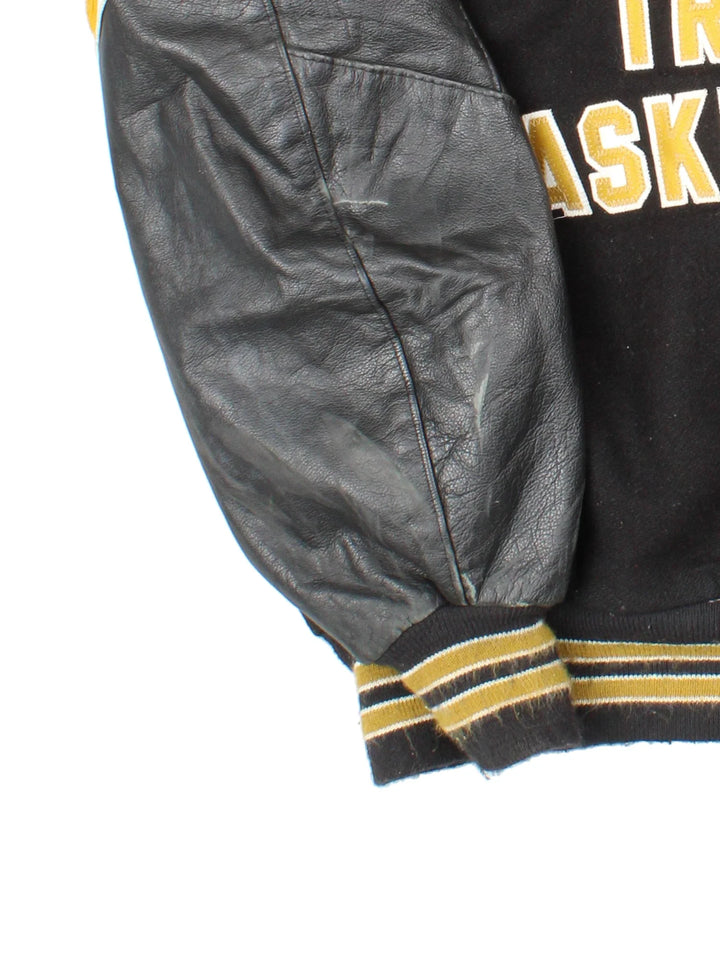 Vintage 'Omaha Burke' College Basketball Varsity Jacket in a black colourway with gold detailing. Classic varsity style with large lettering on the front and spell out on the back, buttons up with side pockets and leather sleeves.