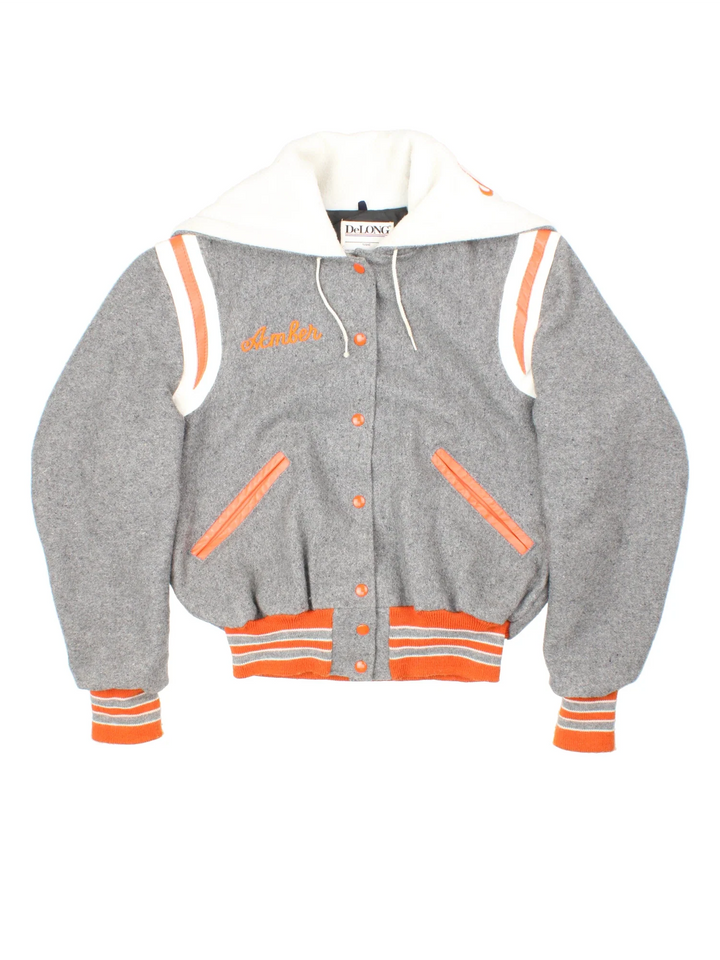 Vintage 80's DeLong Cheerleader Varsity Jacket in a grey colourway with white and orange detailing. Zip up and fold down hood with logo on the reverse and classic button up and double pockets on the front.