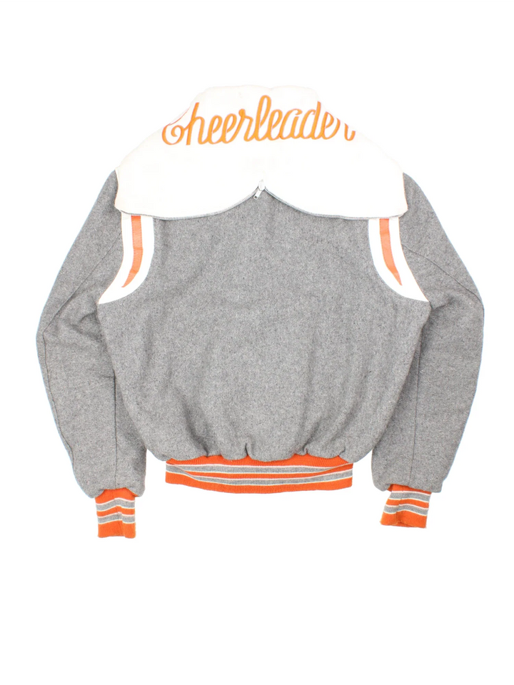 Vintage 80's DeLong Cheerleader Varsity Jacket in a grey colourway with white and orange detailing. Zip up and fold down hood with logo on the reverse and classic button up and double pockets on the front.