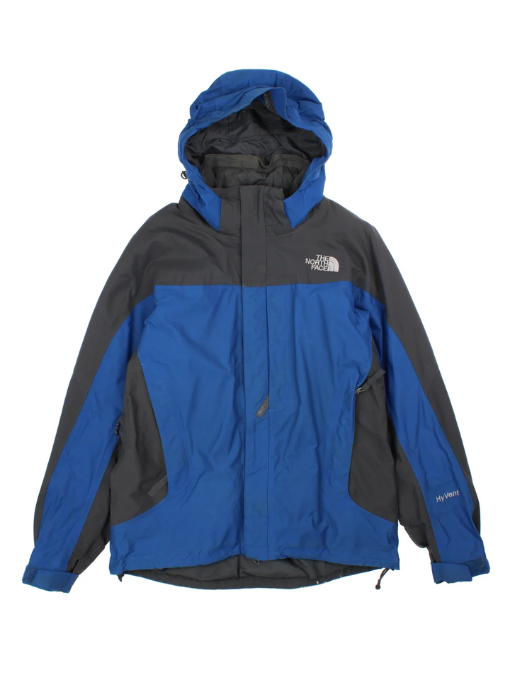 The North Face Hyvent Jacket in a blue colourway with black panelling. Full zip with multiple pockets, drawstring hood and hem with small classic logo on the chest.