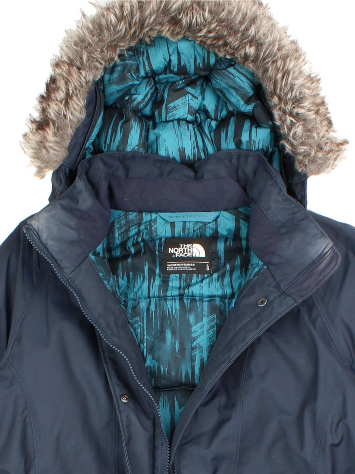 The North Face Parka Coat in a blue colourway with faux fur hood. Full zip with buttons nd two pockets on the side. Small classic logo on the back.