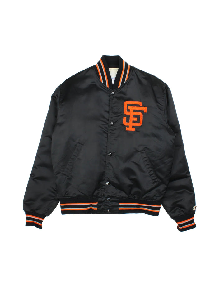 Vintage Starter San Francisco Giants Bomber Jacket in a black colourway with orange and grey detailing. Buttons up and has side pockets, quilted lining, and has the logos embroidered on the front.