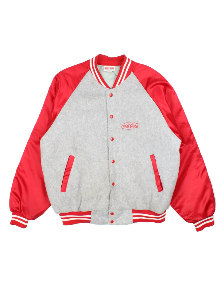 Vintage Coca-Cola Bomber Jacket in a grey colourway with red panelling and detailing. Buttons up and has side pockets, insulated with a quilted lining, and has the logos embroidered on the front.
