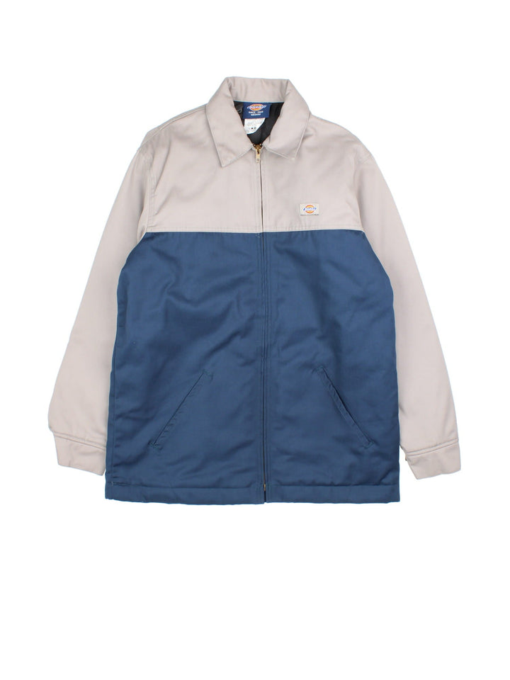 Dickies Eisenhower Jacket in a 2 tone blue and grey colourway. Zips up and has side pockets, insulated with a quilted lining, and has the logo embroidered on the front.