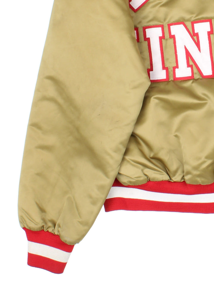Vintage San Francisco 49ers NFL Chalk Line Varsity Jacket in a gold tan colourway. Buttons up and has side pockets, insulated with a quilted lining, and has the team logo and spell out embroidered on the front and back.
