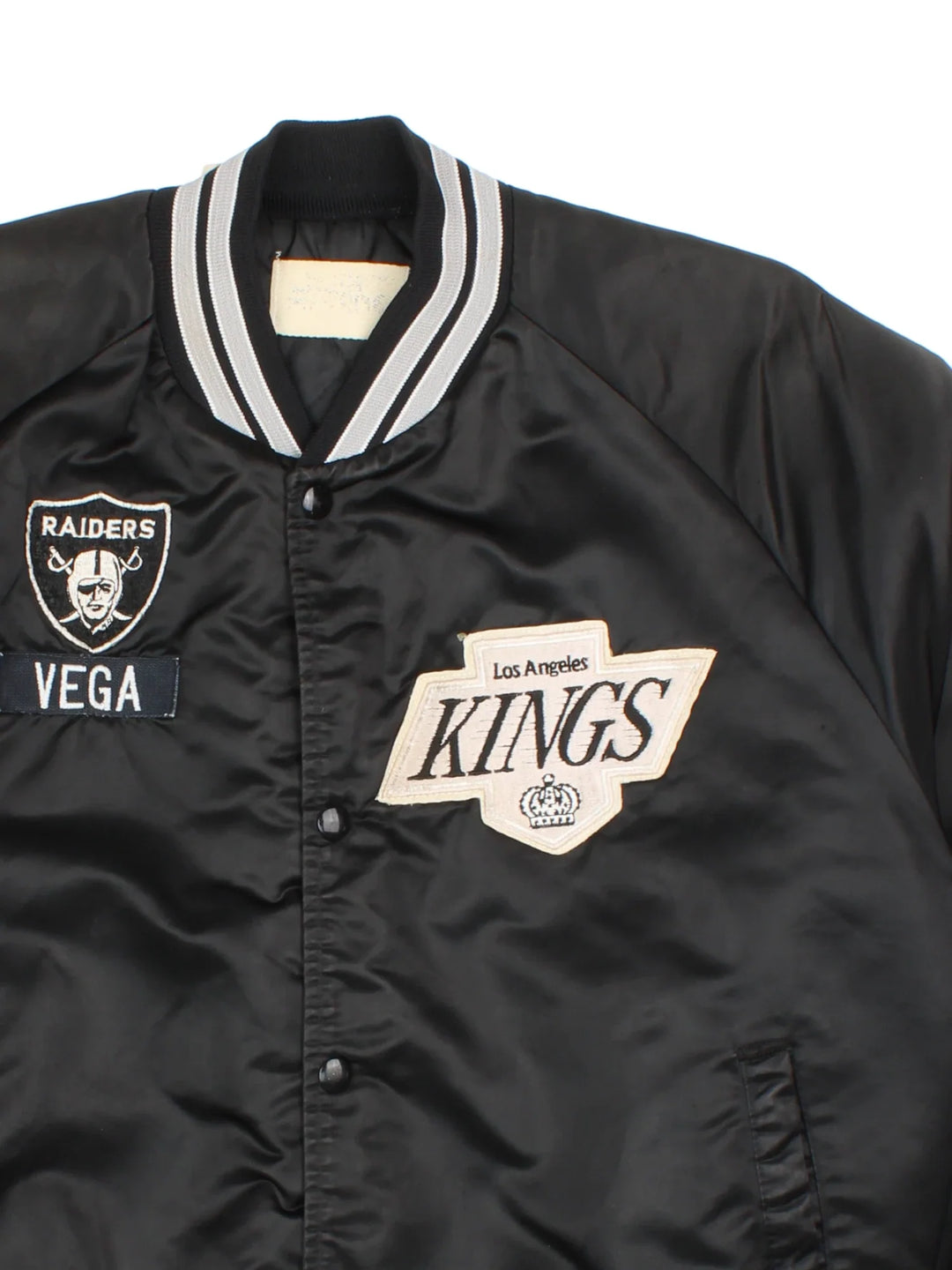 Vintage Los Angeles Kings Varsity Jacket in a black/white colourway. Buttons up with side pockets, contrast cuffs and hem. Logos embroidered on front and back.
