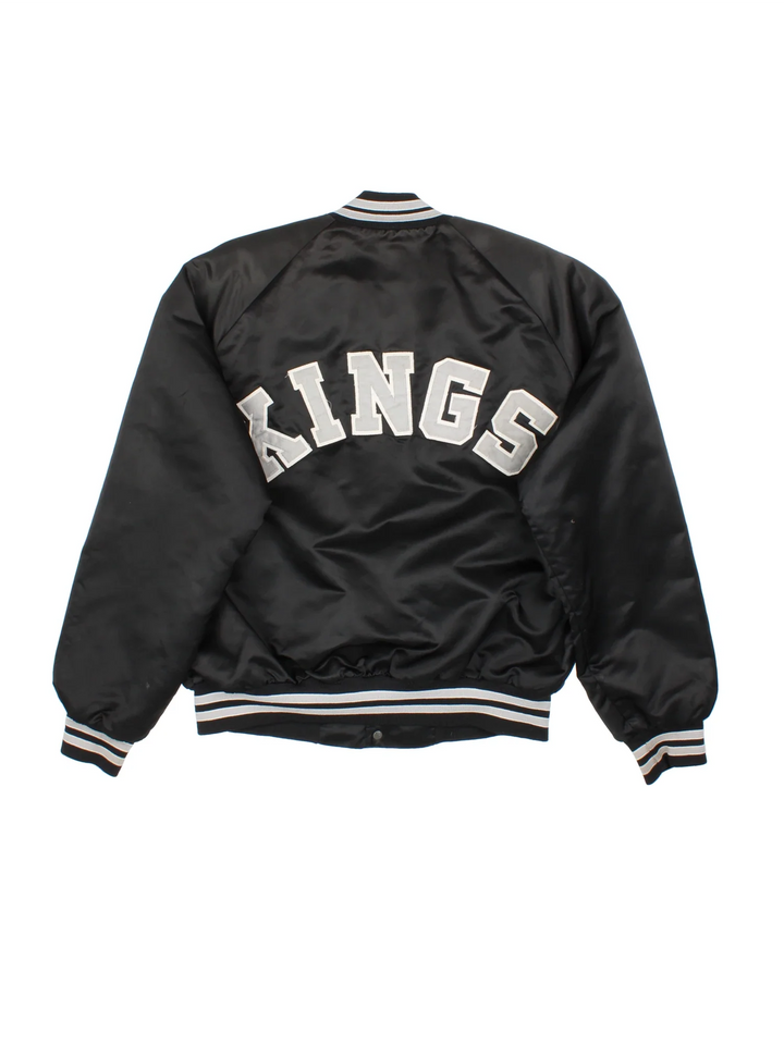 Vintage Los Angeles Kings Varsity Jacket in a black/white colourway. Buttons up with side pockets, contrast cuffs and hem. Logos embroidered on front and back.