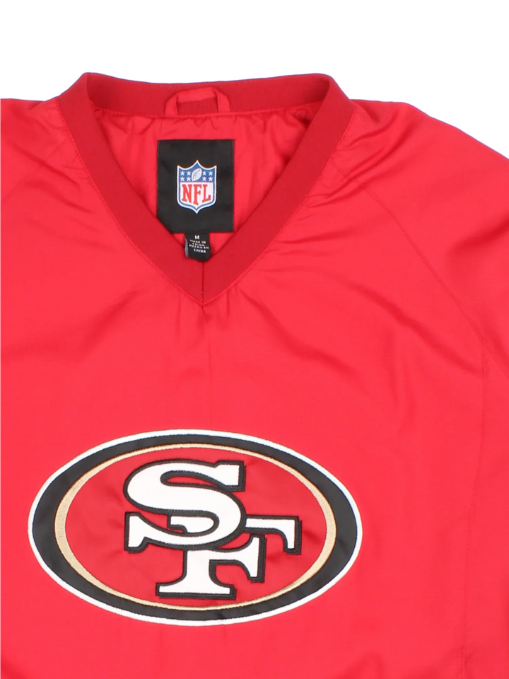 NFL San Francisco 49ers Training Top in a red/grey colourway. Pullover with side pockets, contrast cuffs and hem. Logos embroidered on front and sleeve.