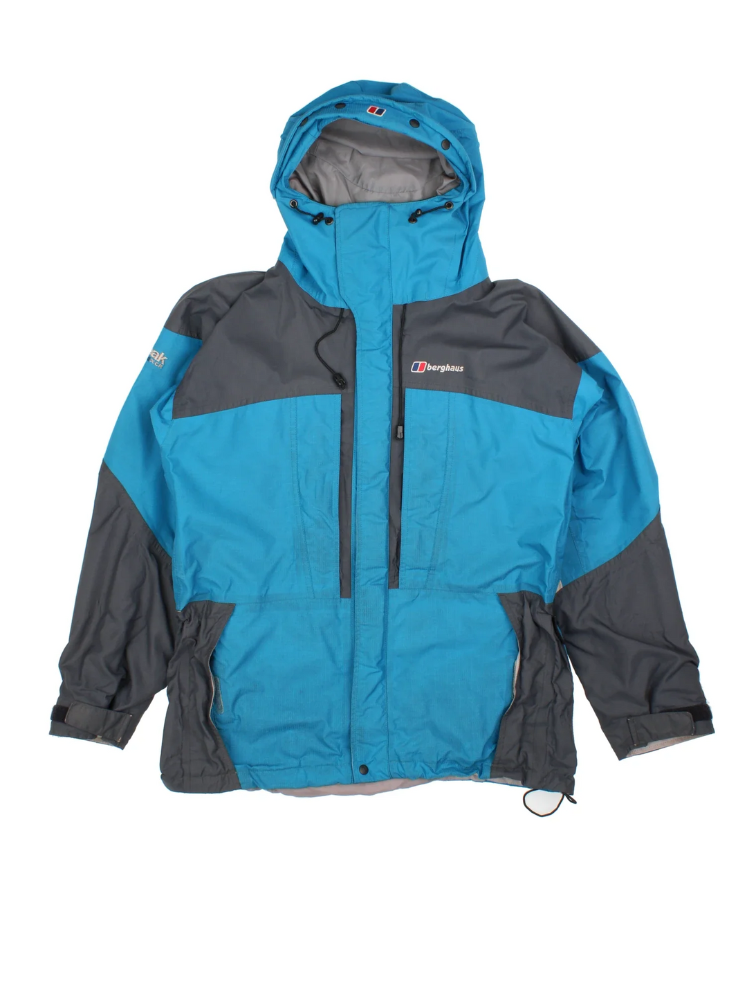 Vintage Berghaus Mera Peak Jacket in a blue colourway with grey tonal panelling. Full button and zip up front with multiple pockets, drawstring hood and small logo on the front.