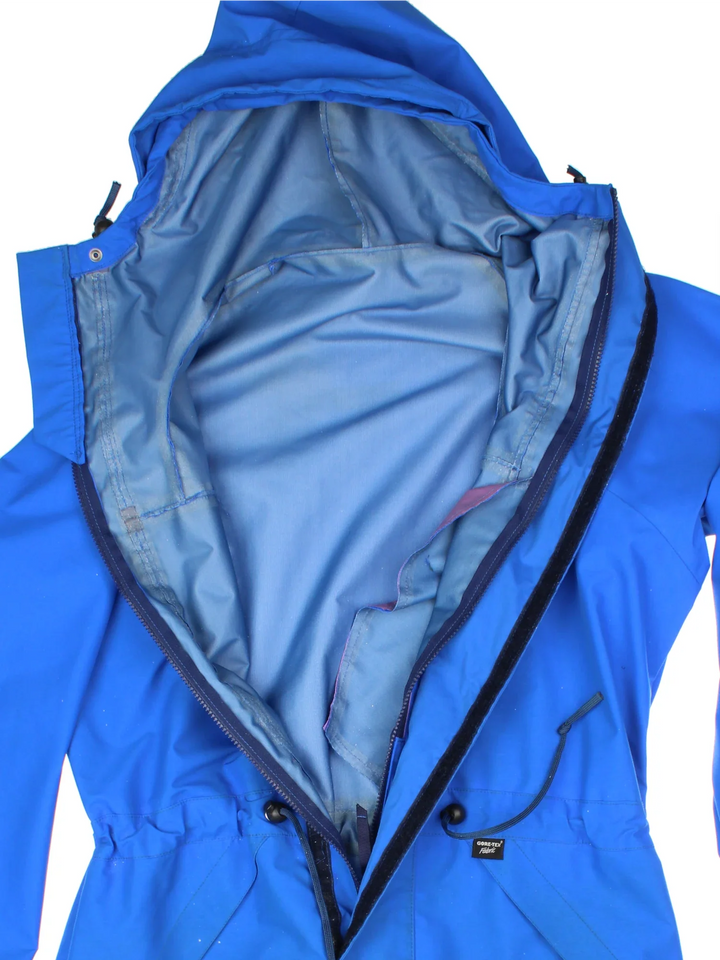 Berghaus Lightning Gore-Tex Jacket in a blue colourway. Full button and zip up front with multiple pockets, drawstring hood and small logo on the front.