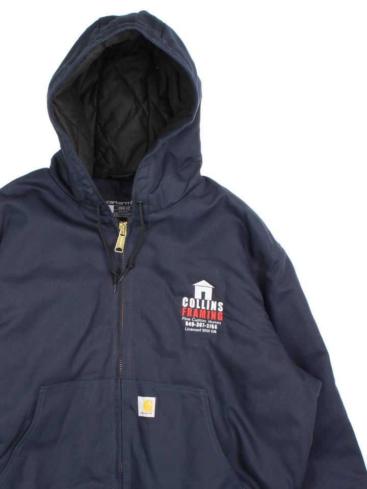 Carhartt Active Jacket in a navy blue colourway. Zips up and has side pockets, insulated with a quilted lining, hooded, and has the Carhartt amd 'Colins Framing' company logo embroidered on the front.