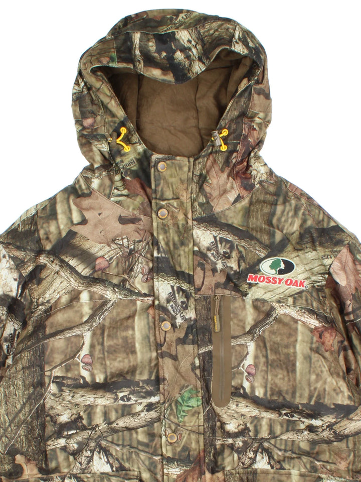Real Tree Mossy Oak Coat in a green colourway. Zips up, with hood and has multiple pockets. Insulated with a quilted lining, and all over pattern.