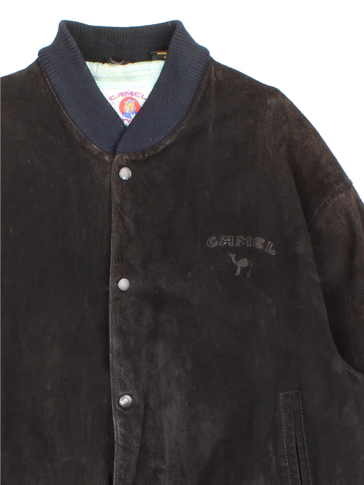 Vintage 90's Camel Suede Bomber Jacket in a black colourway. Buttons up and has side pockets, insulated with a satin lining, and has the logo embroidered on the front.