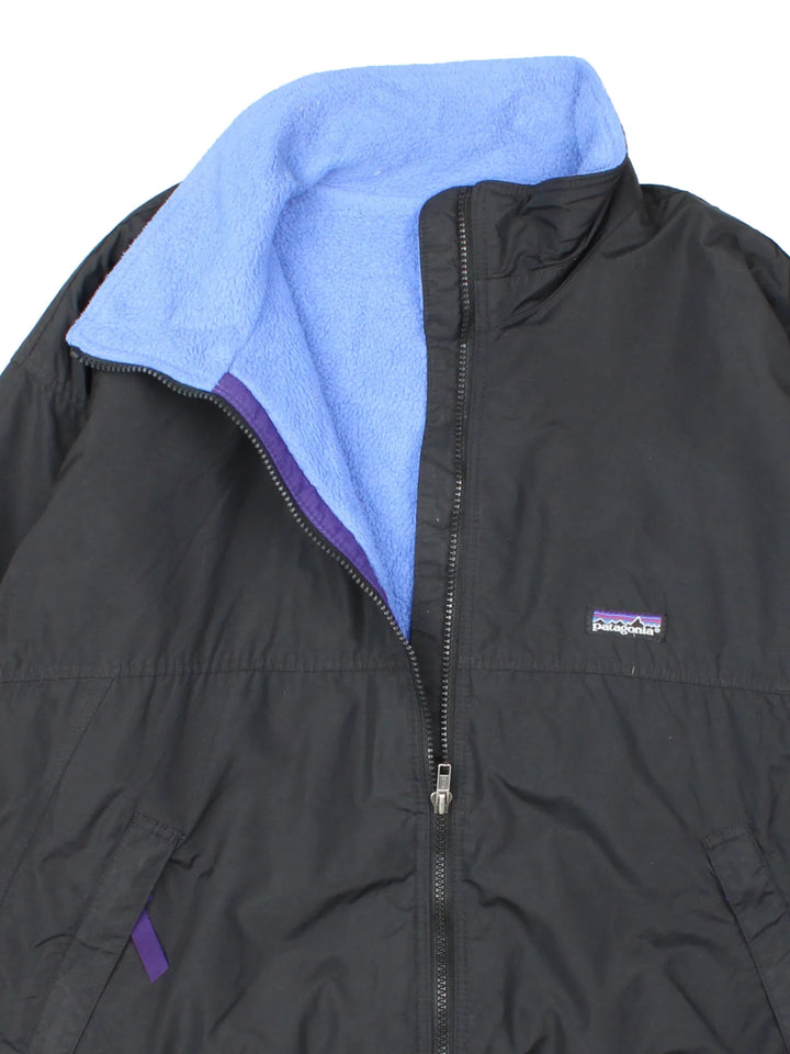Vintage Patagonia Fleece Lined Jacket in a black colourway with blue fleece lining. Full zip up and has side pockets and small classic logo on the front.