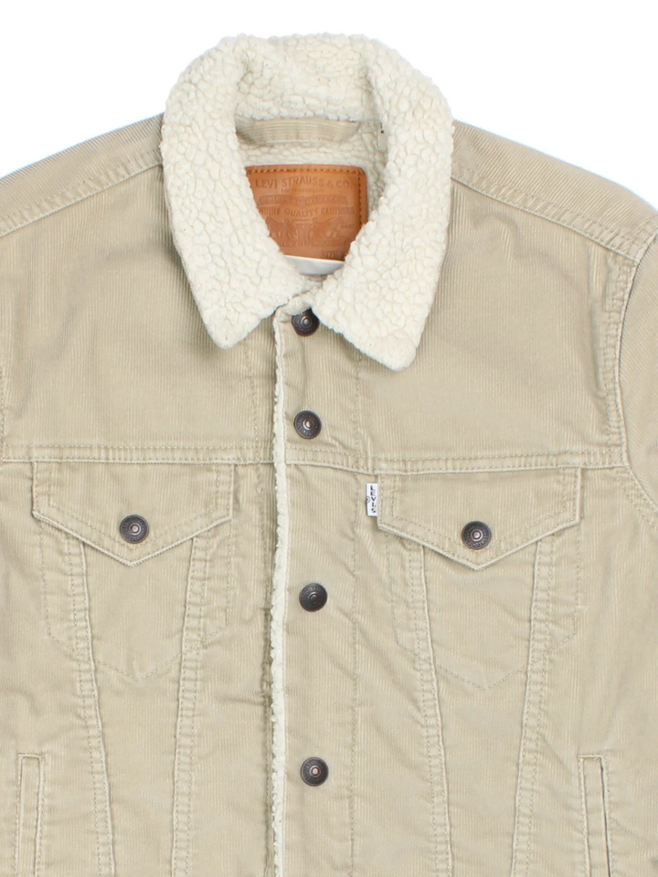 Levi Strauss Sherpa Cord Trucker Jacket in a tan colourway. Buttons up and has multiple pockets, insulated lining, and has the logo tab embroidered on the front.