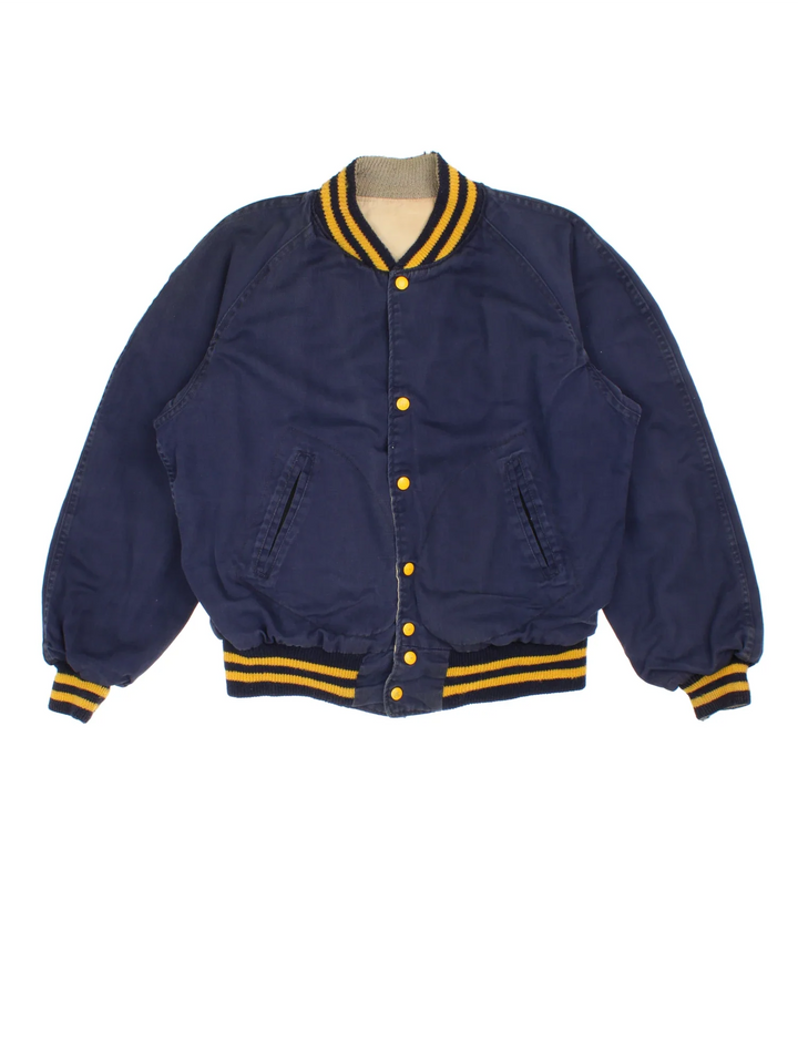 Vintage 1960's Notre Dame Varsity Jacket in a blue and yellow colourway. Buttons up and has side pockets, and has the spell out embroidered on the back.
