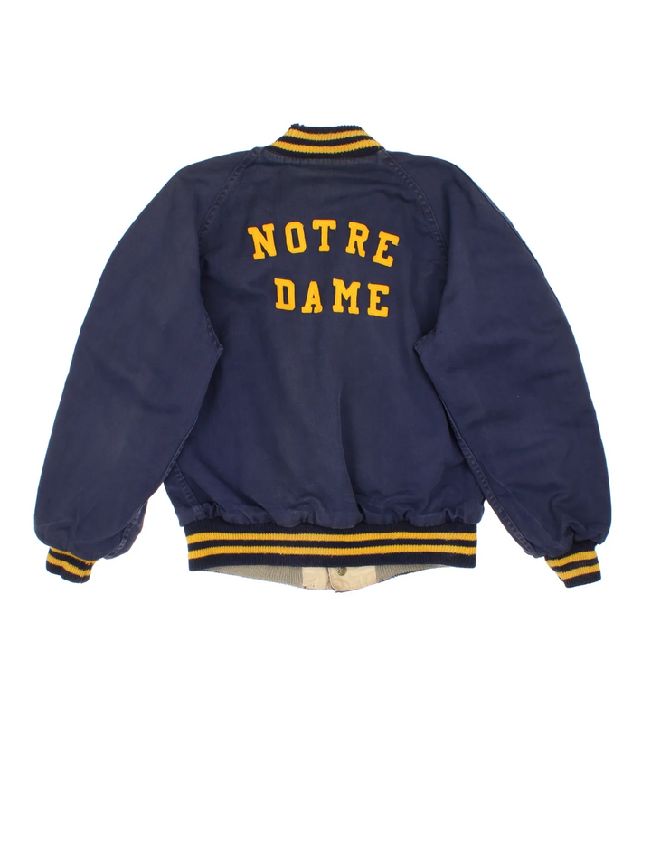Vintage 1960's Notre Dame Varsity Jacket in a blue and yellow colourway. Buttons up and has side pockets, and has the spell out embroidered on the back.