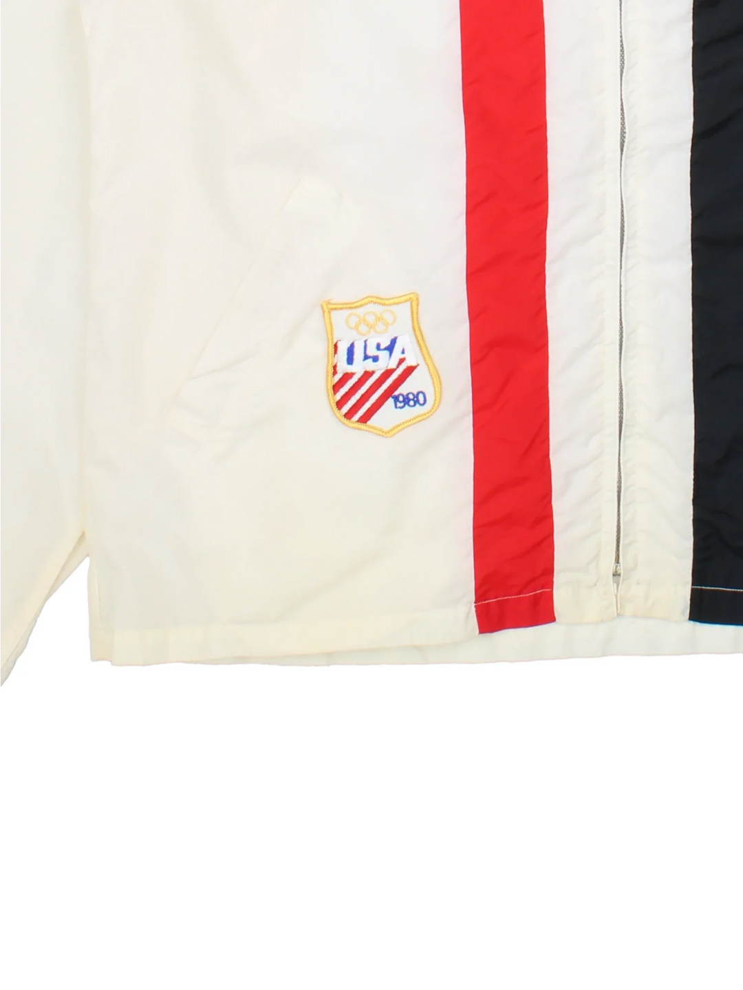 Vintage 1980 USA Team Olympics Nylon Jacket Jacket in a white colourway with a red and black stripe going down the front. Zips up and has side pockets, hooded and the USA Team logo embroidered on the front.