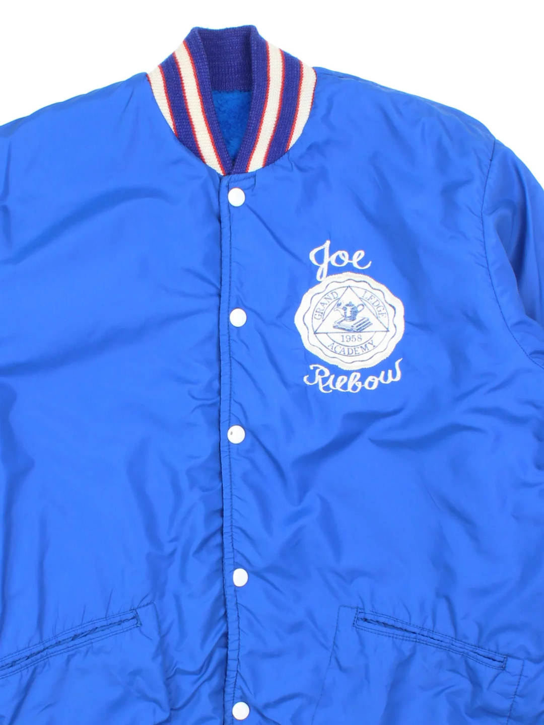 Vintage 1958 Grand Ledge Varsity Jacket in a blue colourway. Popper fastening and has side pockets, elasticated collar/cuffs and embroidered detail on the front/sleeve.