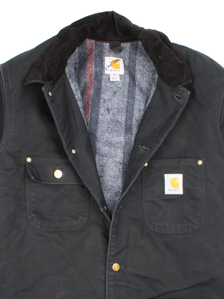 Carhartt Chore Jacket in a black colourway. Buttons up and has multiple pockets, and has the logo embroidered on the front.