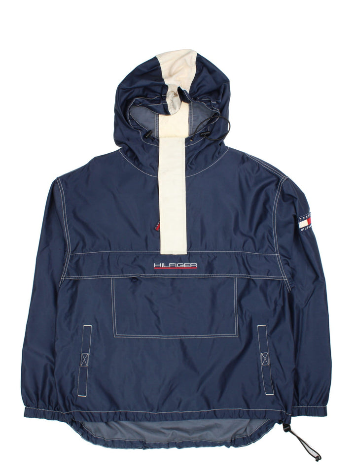 Tommy Hilfiger Pullover Jacket in a blue colourway with striped pattern hood. 1/4 zip with buttoned overlay, Large zip pocket on the front with two side pockets, Classic logo on the front and arm, and also a drawstring hood and hem.