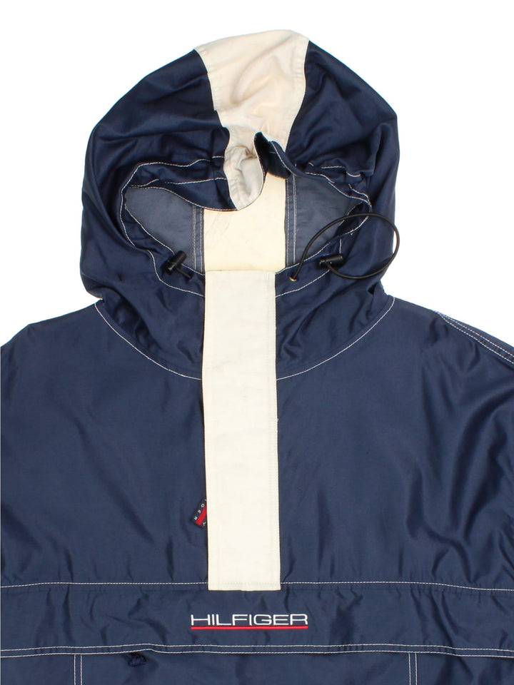 Tommy Hilfiger Pullover Jacket in a blue colourway with striped pattern hood. 1/4 zip with buttoned overlay, Large zip pocket on the front with two side pockets, Classic logo on the front and arm, and also a drawstring hood and hem.