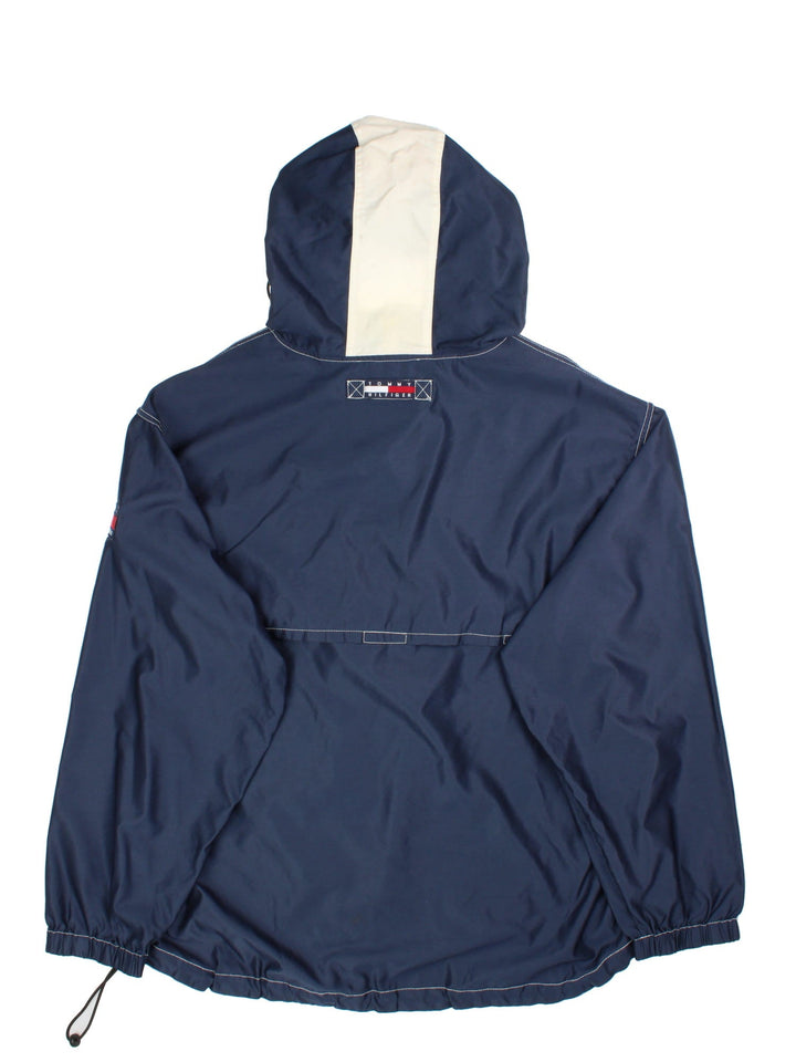 Tommy Hilfiger Pullover Jacket in a blue colourway with striped pattern hood. 1/4 zip with buttoned overlay, Large zip pocket on the front with two side pockets, Classic logo on the front and arm, and also a drawstring hood and hem.