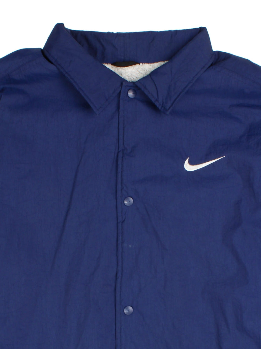 Nike Coach Jacket in a blue colourway. Fleece lining with full button up front, double zip pocket with small classic nike swoosh. Large Nike logo across the back.