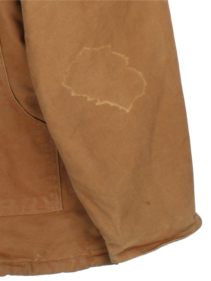 Carhartt Arctic Jacket in a brown colourway with a corduroy collar. Zips up and has multiple pockets, insulated with a quilted lining, and has the logo embroidered on the front.