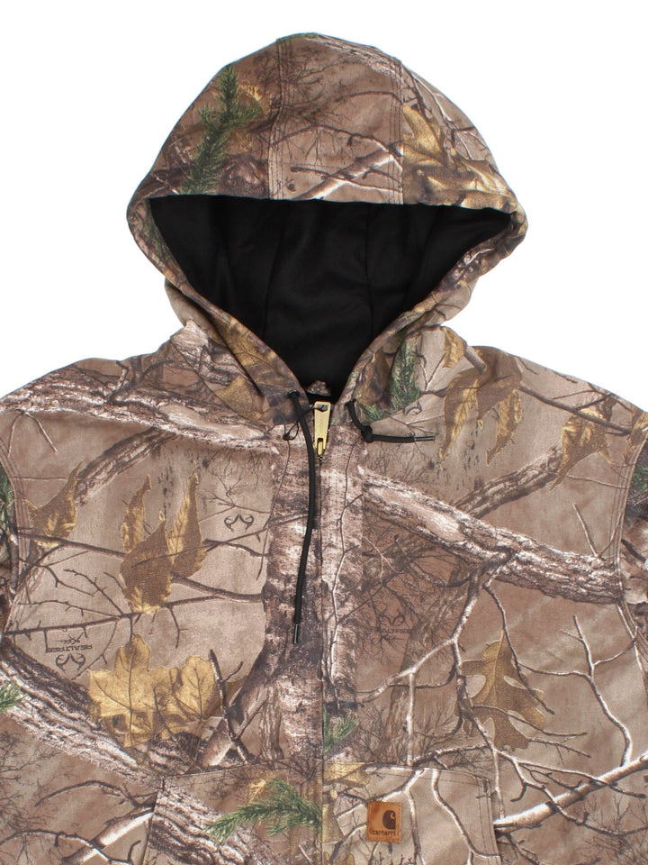 Carhartt Real Tree Camo Active Jacket in a brown and green colourway. Zips up and has side pockets, hooded, and has the logo embroidered on the front.