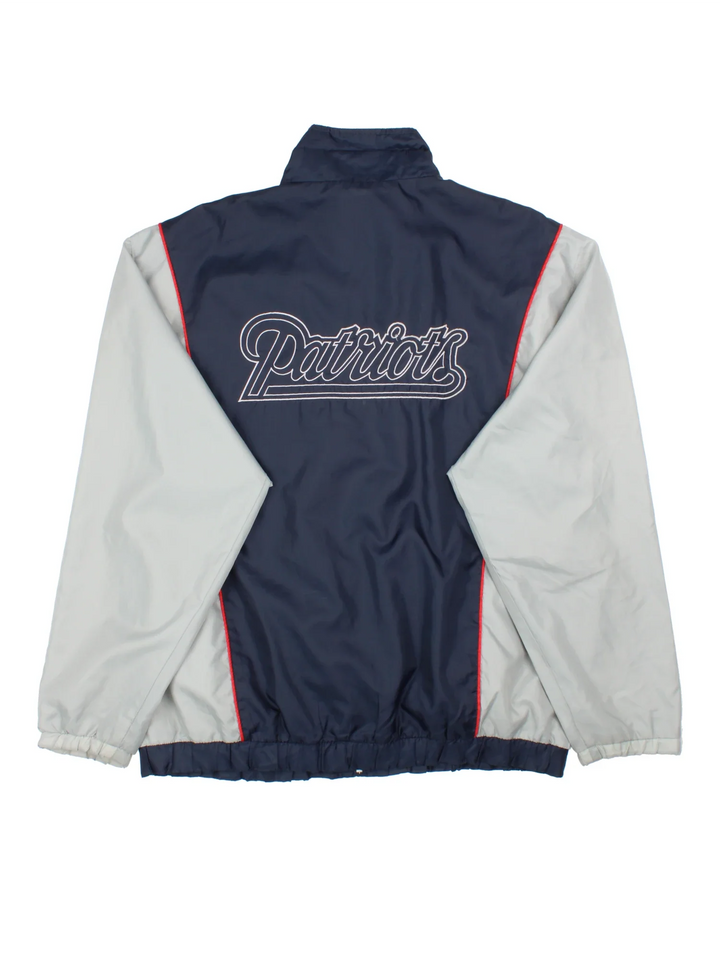 New England Patriots NFL Windbreaker Jacket in a blue colourway with grey panelling. Full zip up, multiple pockets, small logo on the front and large text logo across the back.