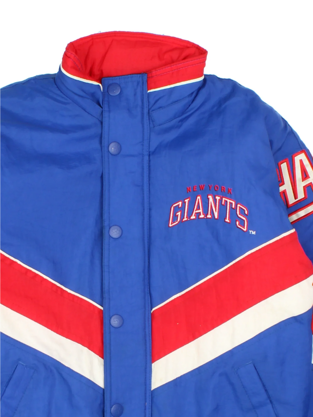 New York Giants Starter NFL Jacket in a blue colourway with red and white panelling. Full zip and button up front, multiple pockets, small logo on the front and across the back.