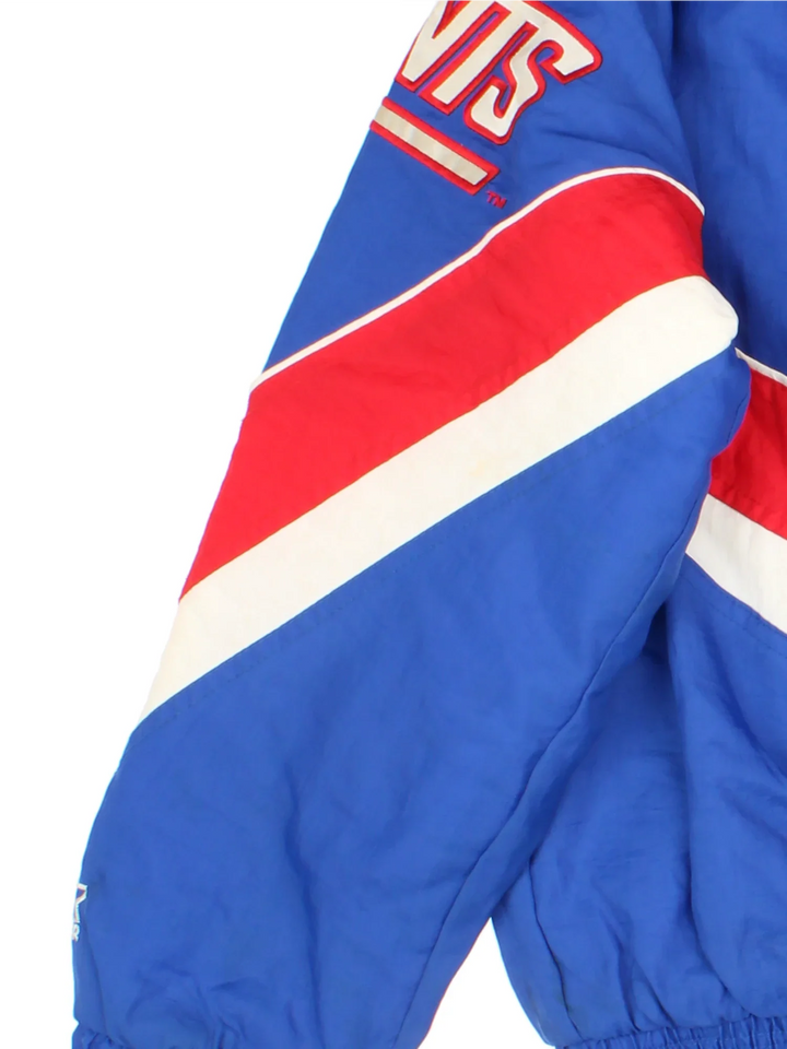New York Giants Starter NFL Jacket in a blue colourway with red and white panelling. Full zip and button up front, multiple pockets, small logo on the front and across the back.