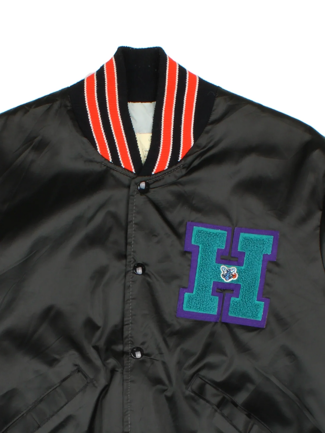 Vintage Charlotte Hornets NBA Satin Varsity Jacket in a black colourway with orange detailing. Full button up front, multiple pockets and small logo on the front. Large team logo across the back.