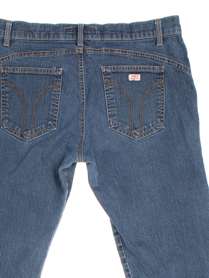 Y2K Miss Sixty Flared Popper Jeans in blue colourway with multiple pockets, popper buttons on the side of the legs, and the logo embroidered on the back.